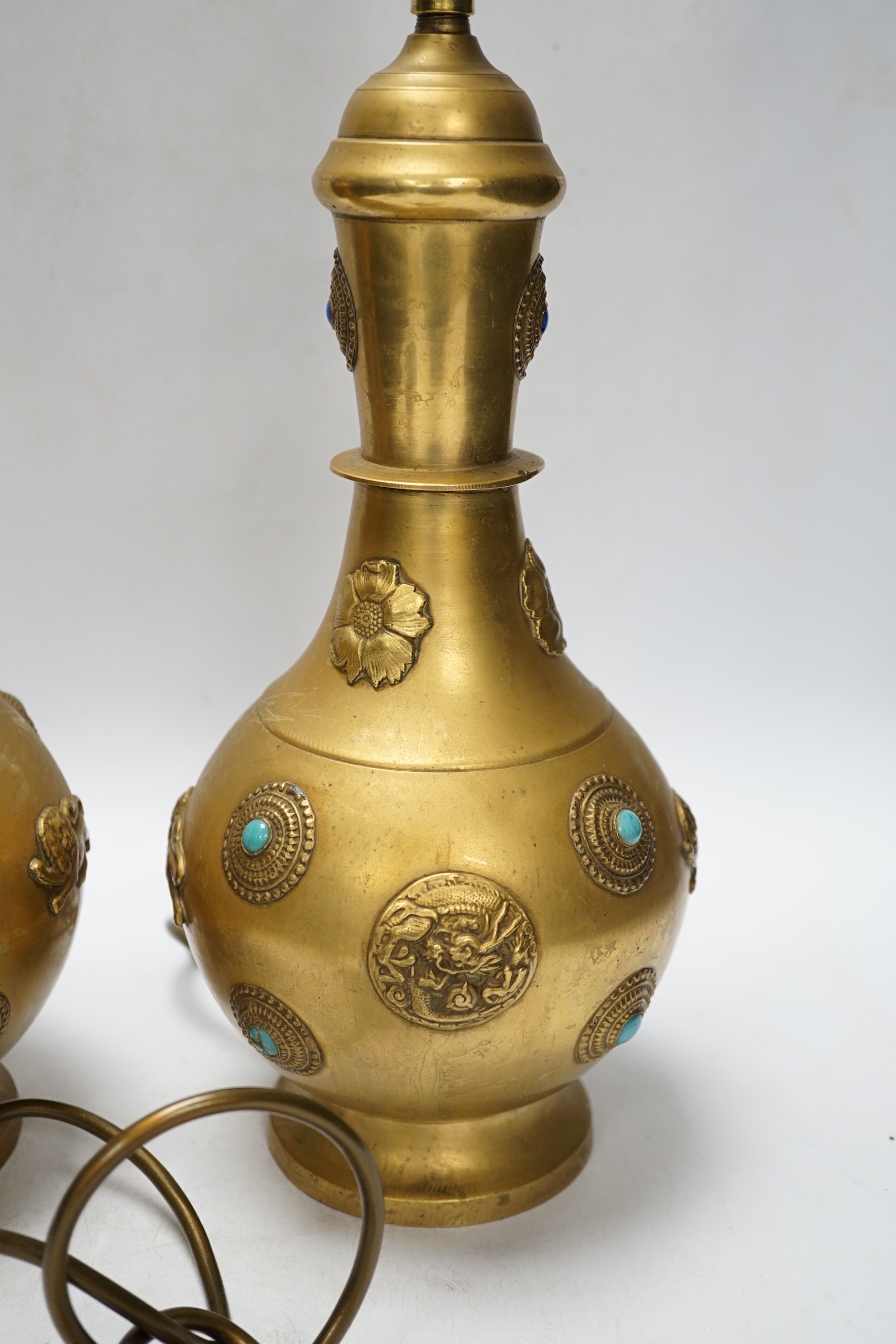 A pair of Sino-Tibetan gilt metal lamp bases set with cabochon stones
